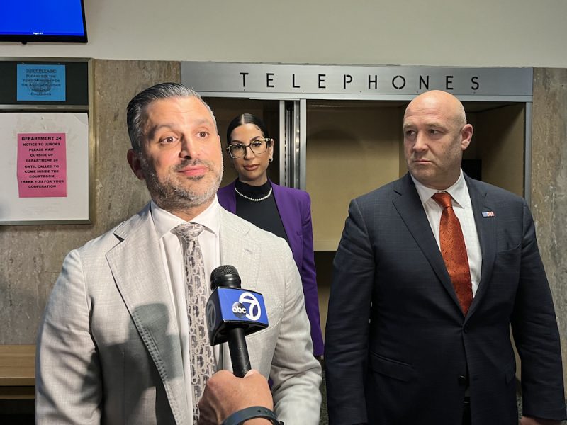 A man in a suit and tie standing in front of a phone booth.