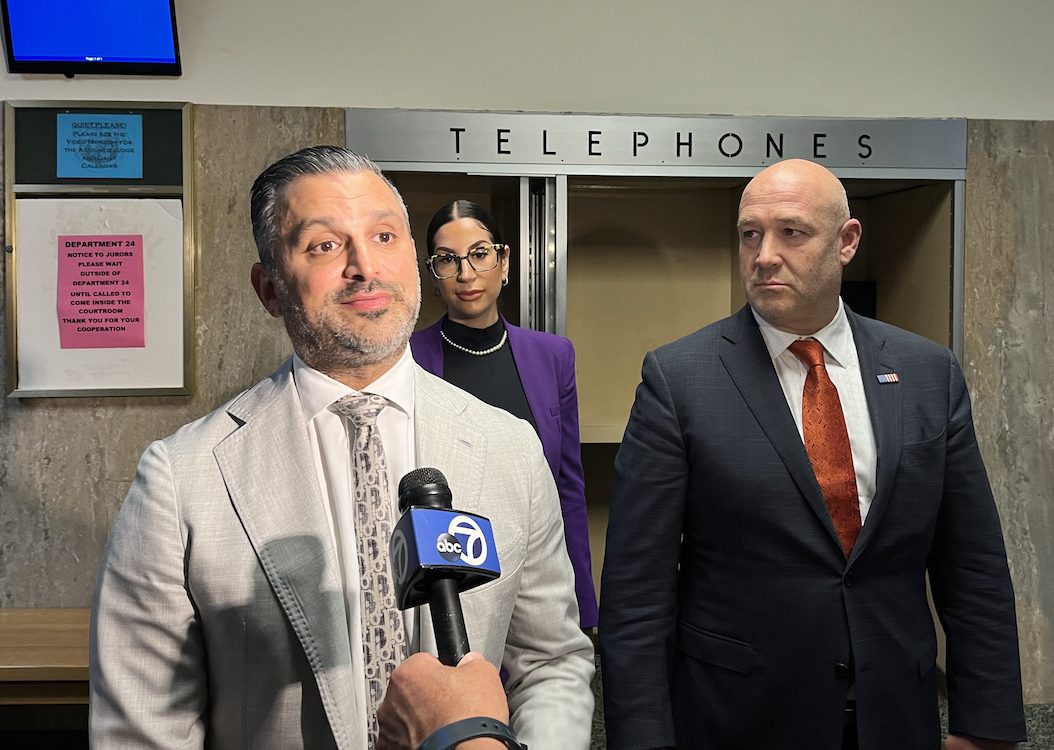 A man in a suit and tie standing in front of a phone booth.