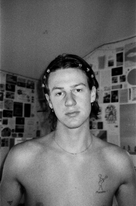 A black and white photo of a young man with tattoos.