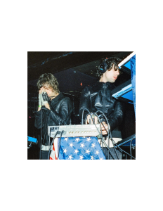 Two djs on stage with an american flag behind them.