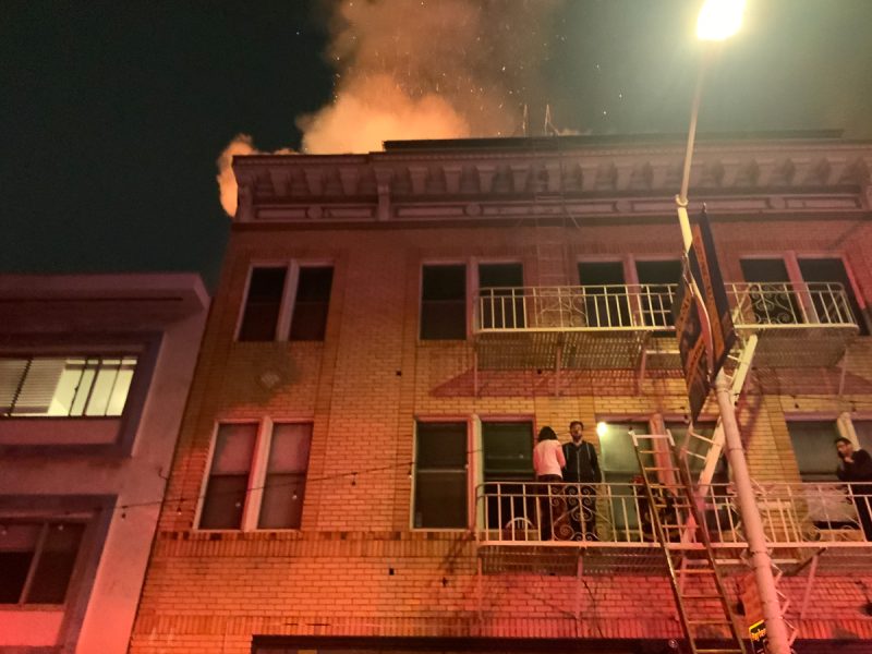 A fire erupts from a building at night.