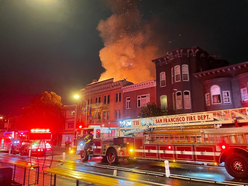 A fire erupts from a building at night.