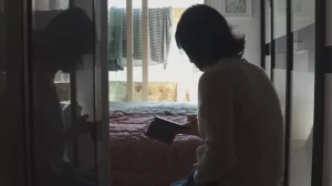 A woman is standing in front of a closet looking at her phone.