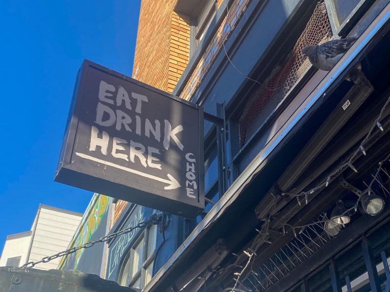 A sign that says eat drink here on the side of a building.