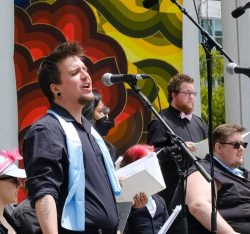 A man singing in front of a group of people.