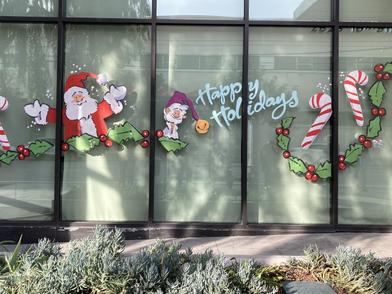 Santa Claus and candy canes are painted on the windows of a building.