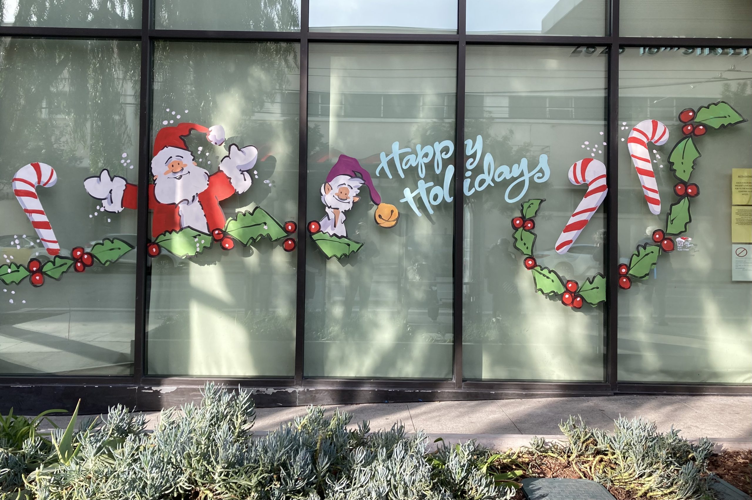 Santa Claus and candy canes are painted on the windows of a building.
