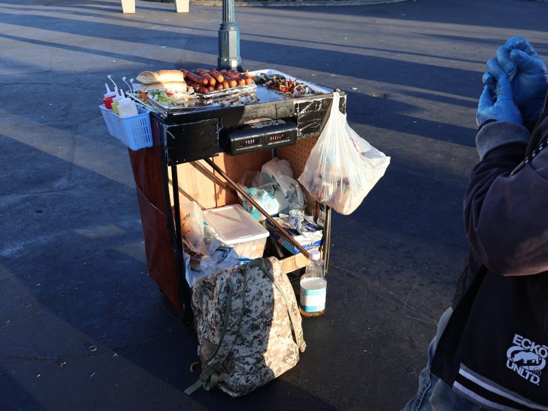 A man is standing next to a cart with food on it.