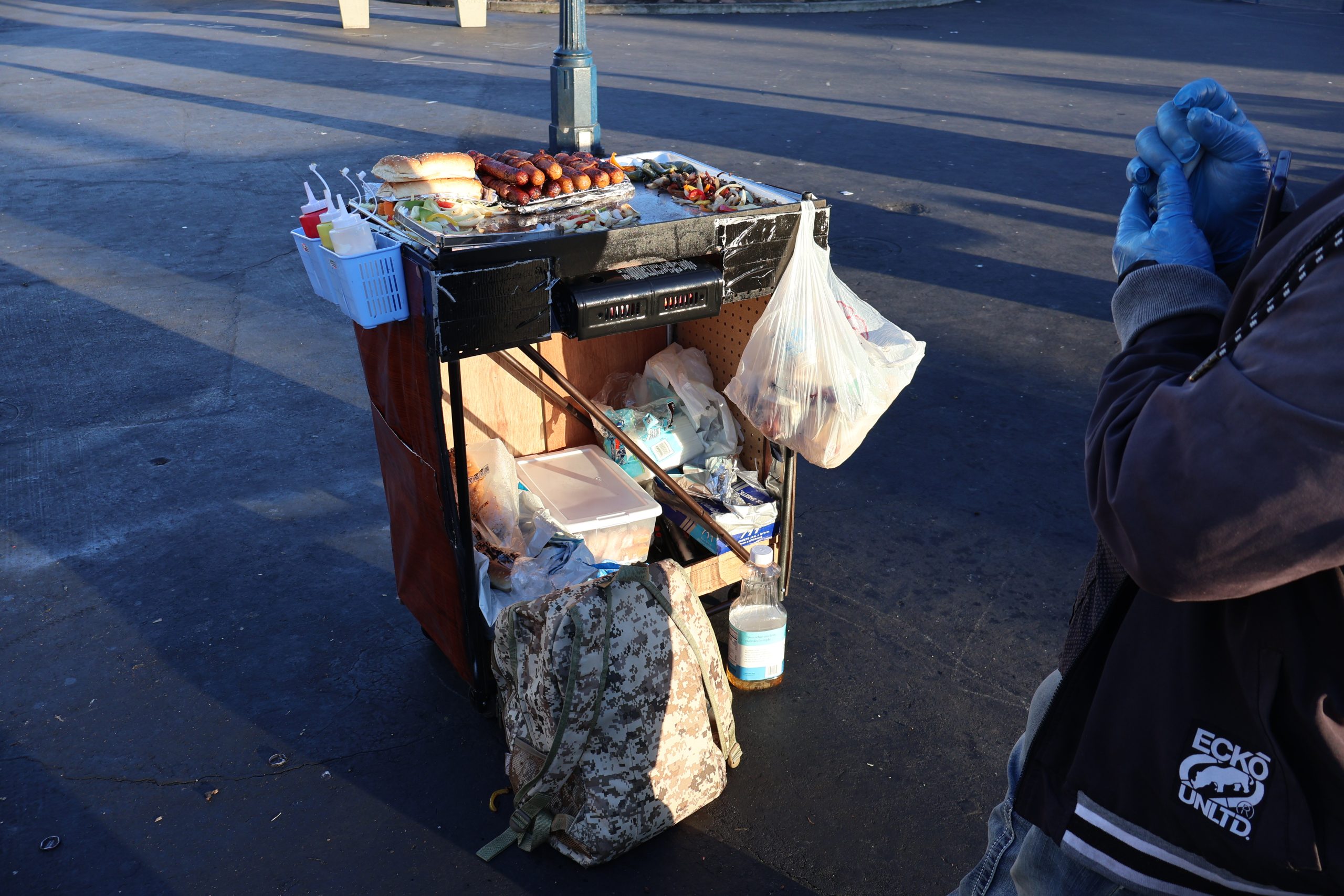 A man is standing next to a cart with food on it.