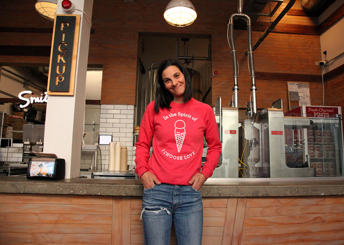 A woman in a red sweatshirt standing in front of a counter.