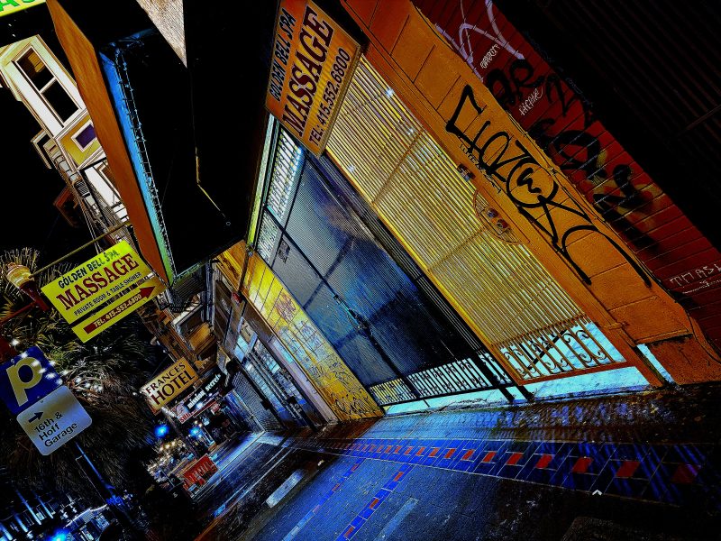A city street at night with graffiti on the side of a building and a sign that says "Massage."