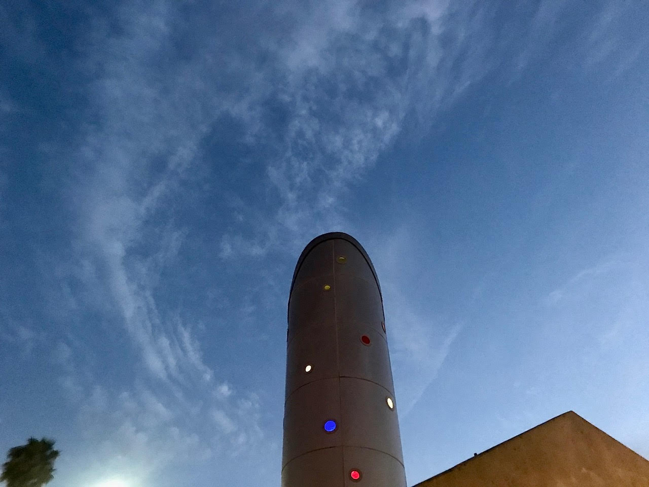 A tall monolithic building with colorful lights on it.