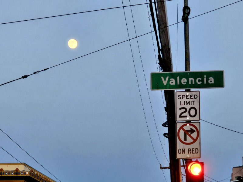 A full moon rises over Valencia Street.