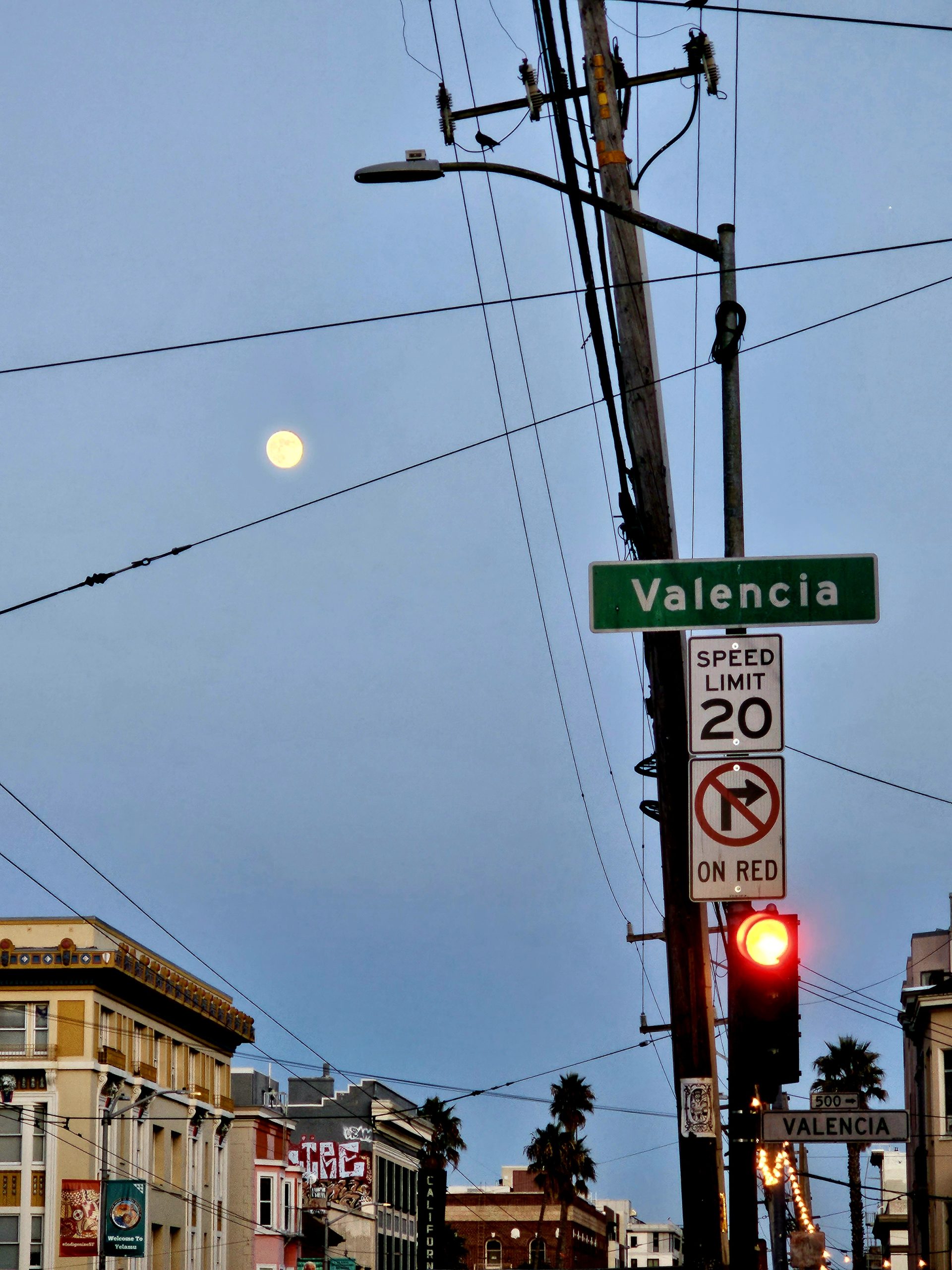 A full moon rises over Valencia Street.