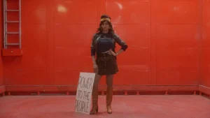 A woman holding a sign in front of a red room.