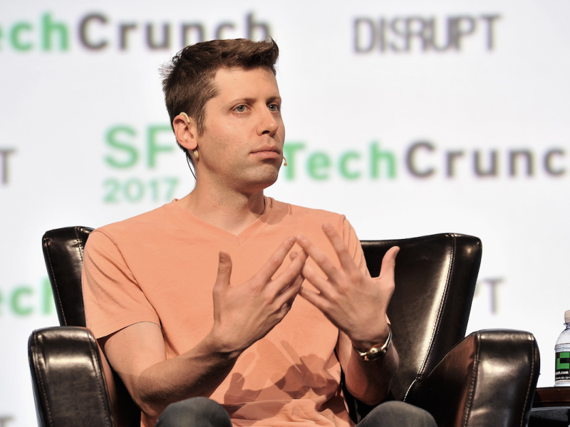 Sam Altman sitting in a chair at a TechCrunch event.