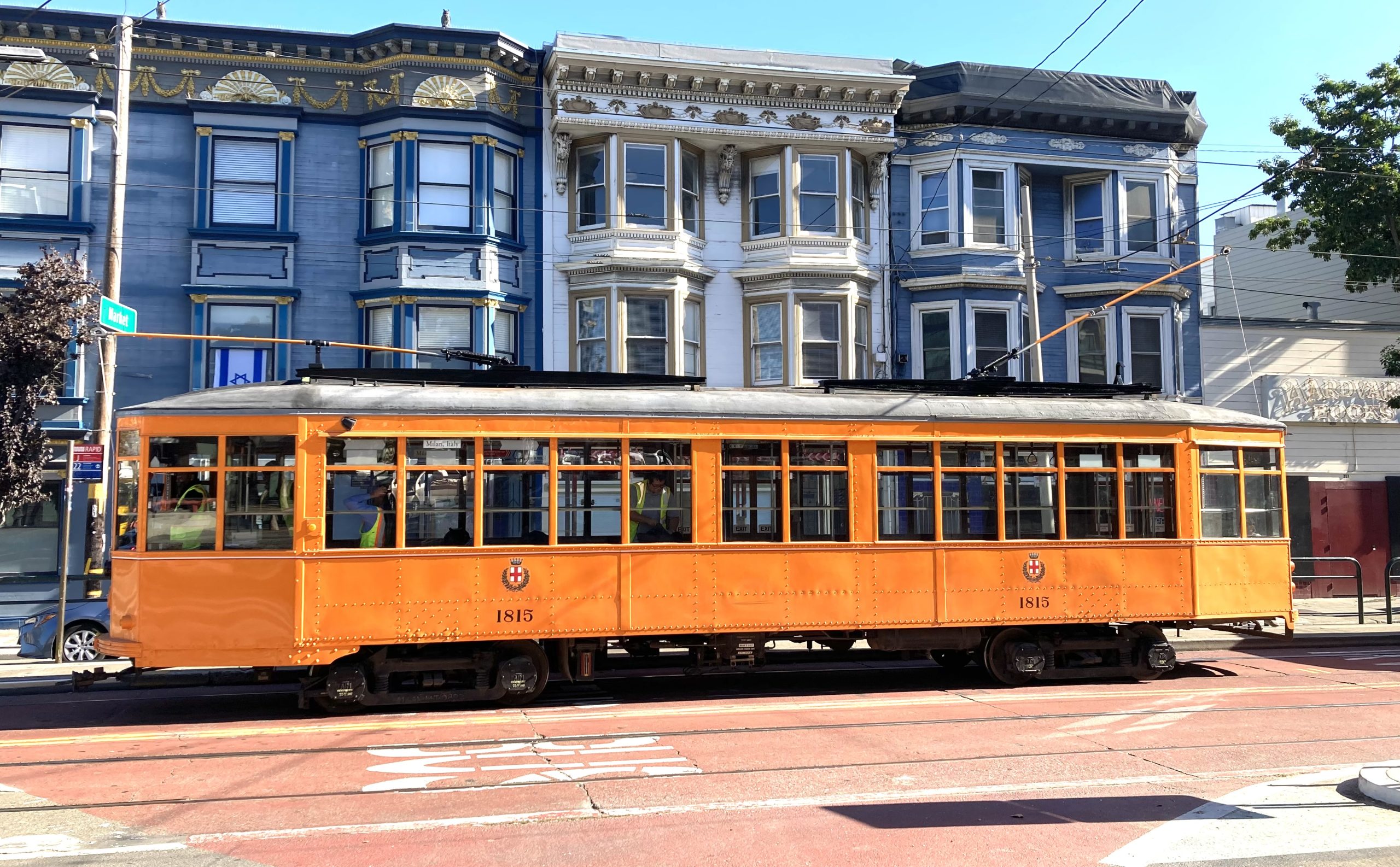 A yellow trolley car on a street in San Francisco.