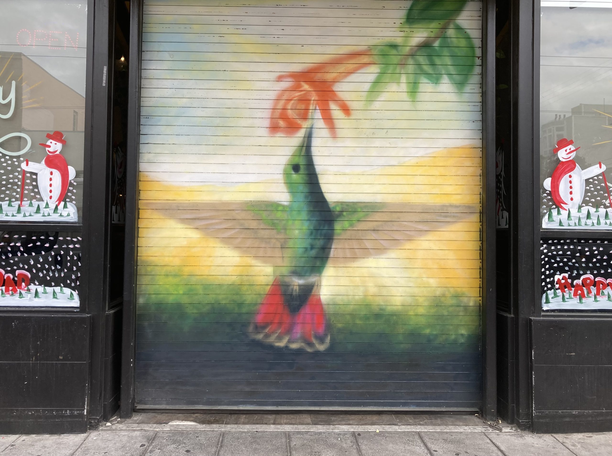 A hummingbird is painted on the door of a store.