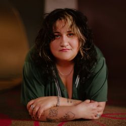 A woman with tattoos laying on the floor.
