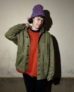 A woman wearing a green jacket and a colorful hat.