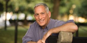 A man leaning against a fence in a park.