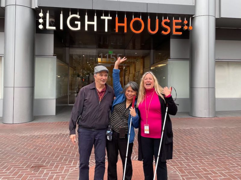 Three individuals posing in front of LightHouse.