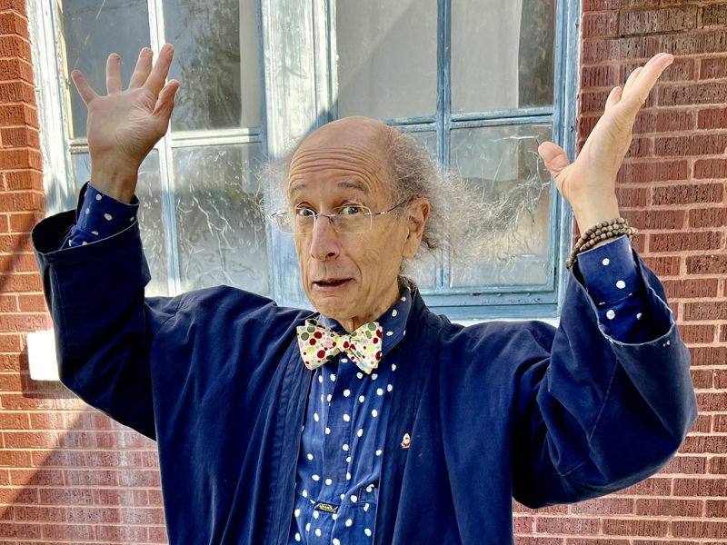 A man in a blue jacket with his hands up in the air.