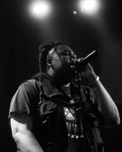 A man with dreadlocks singing into a microphone.