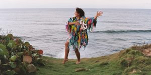A woman is standing on a grassy hill next to the ocean.