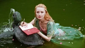 A woman in a green dress sitting on a turtle.