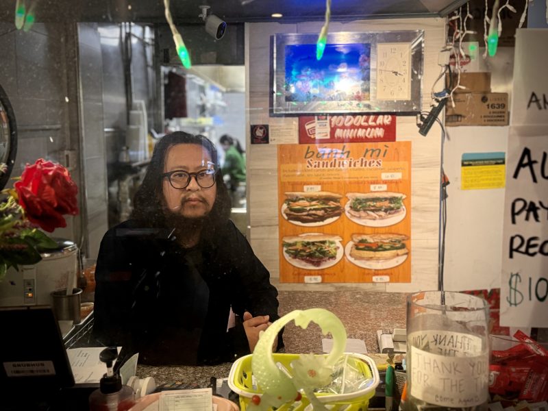 A man in black shirt standing behind a register.