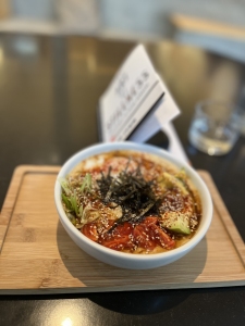 A bowl of ramen sitting on top of a wooden tray.