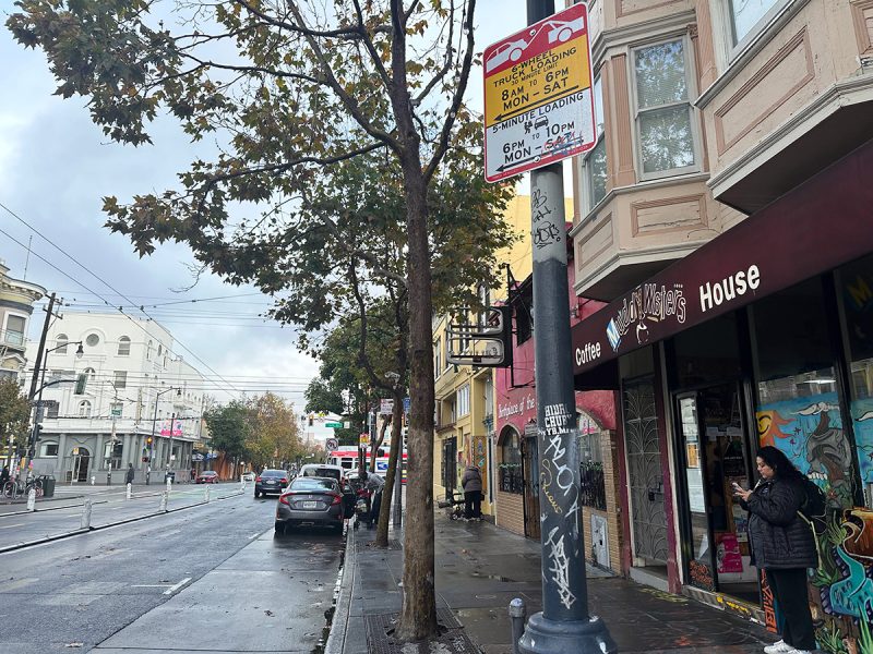 A woman is standing on a sidewalk next to a store.