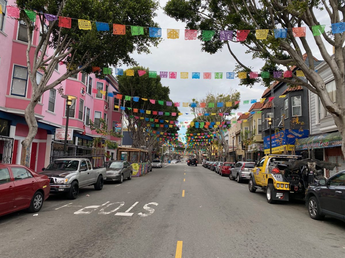 A street in san francisco with colorful flags hanging from the trees.