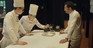 Three chefs preparing food in a kitchen.