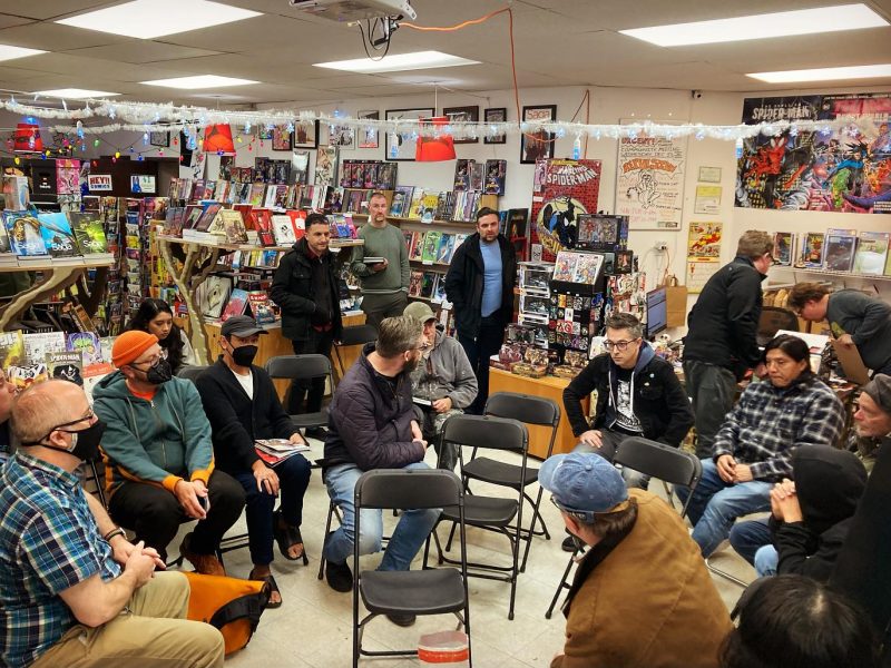 A group of people sitting in a circle at a comic book store