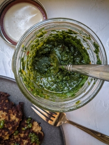 A jar of pesto sauce on a plate next to a plate of fajitas.