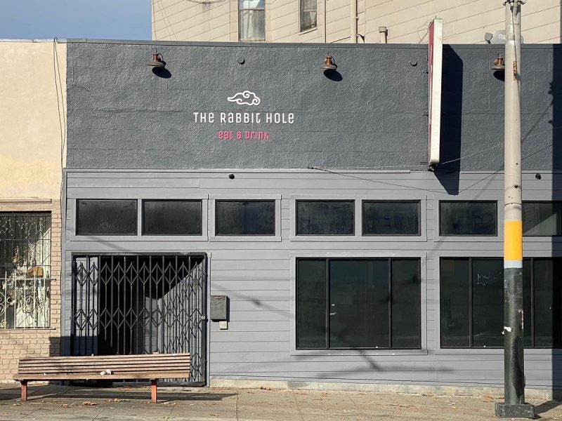 Dark gray storefront of a restaurant and bar called "The Rabbit Hole".