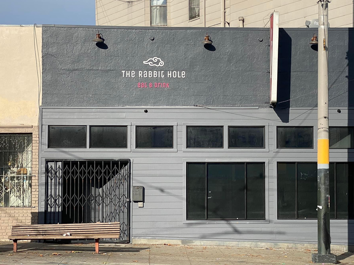 Dark gray storefront of a restaurant and bar called "The Rabbit Hole".