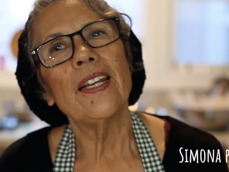 A woman wearing glasses and an apron in a kitchen.