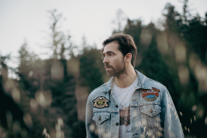 A man in a denim jacket standing in a field.
