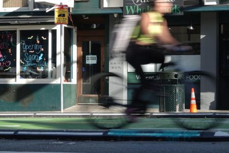 A person riding a bike in front of a store.