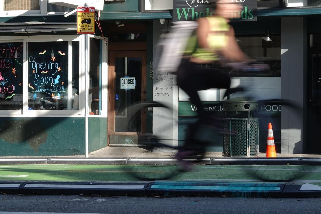 A person riding a bike in front of a store.