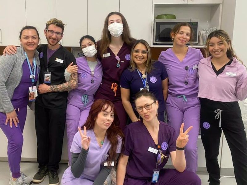A group of nurses from Planned Parenthood in purple scrubs posing for a photo.