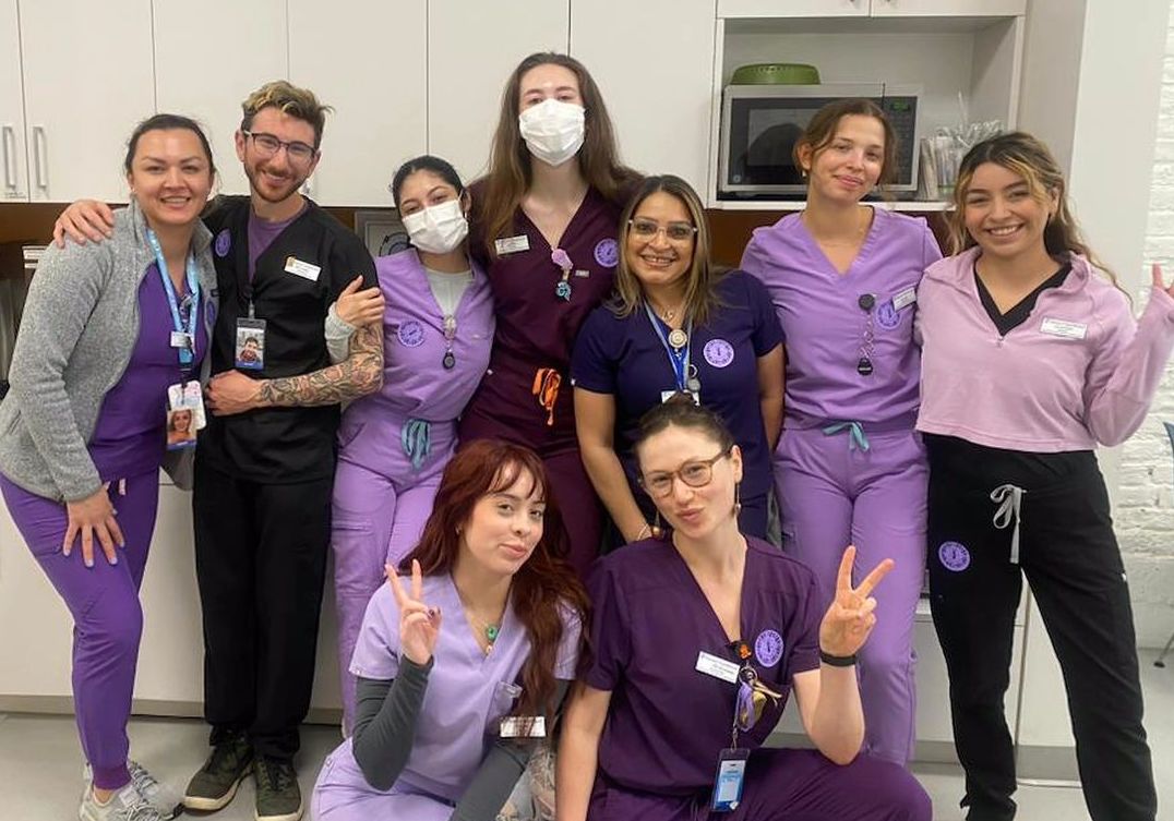 A group of nurses from Planned Parenthood in purple scrubs posing for a photo.