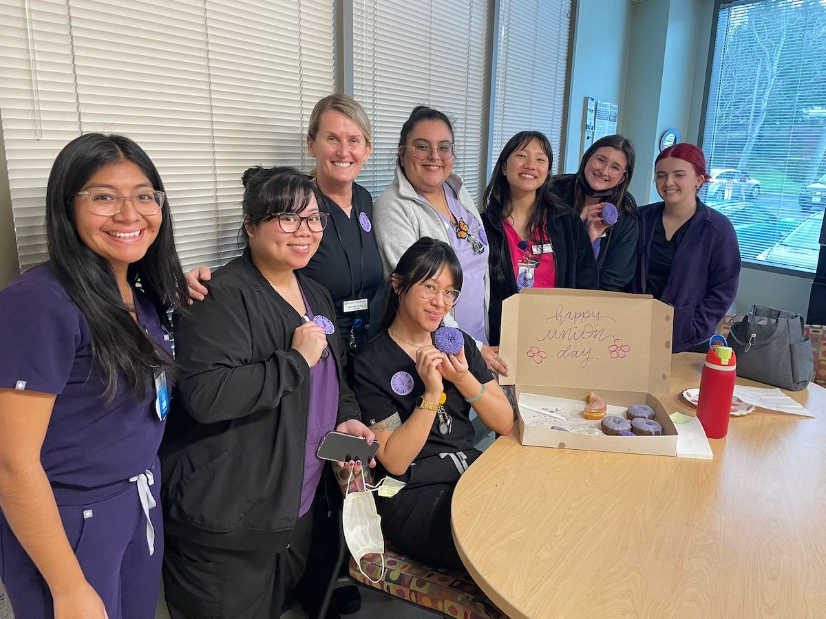 A group of nurses from Planned Parenthood Northern California (PPNorCal) posing in front of a box of donuts.