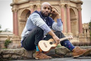 A man sitting on a rock with a ukule.