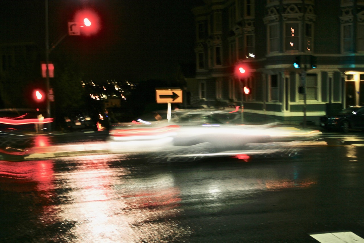 A blurry picture of a car driving down a rainy street at night.