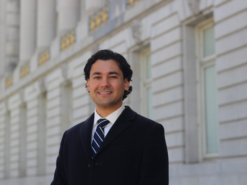 A man in a suit standing in front of a building.
