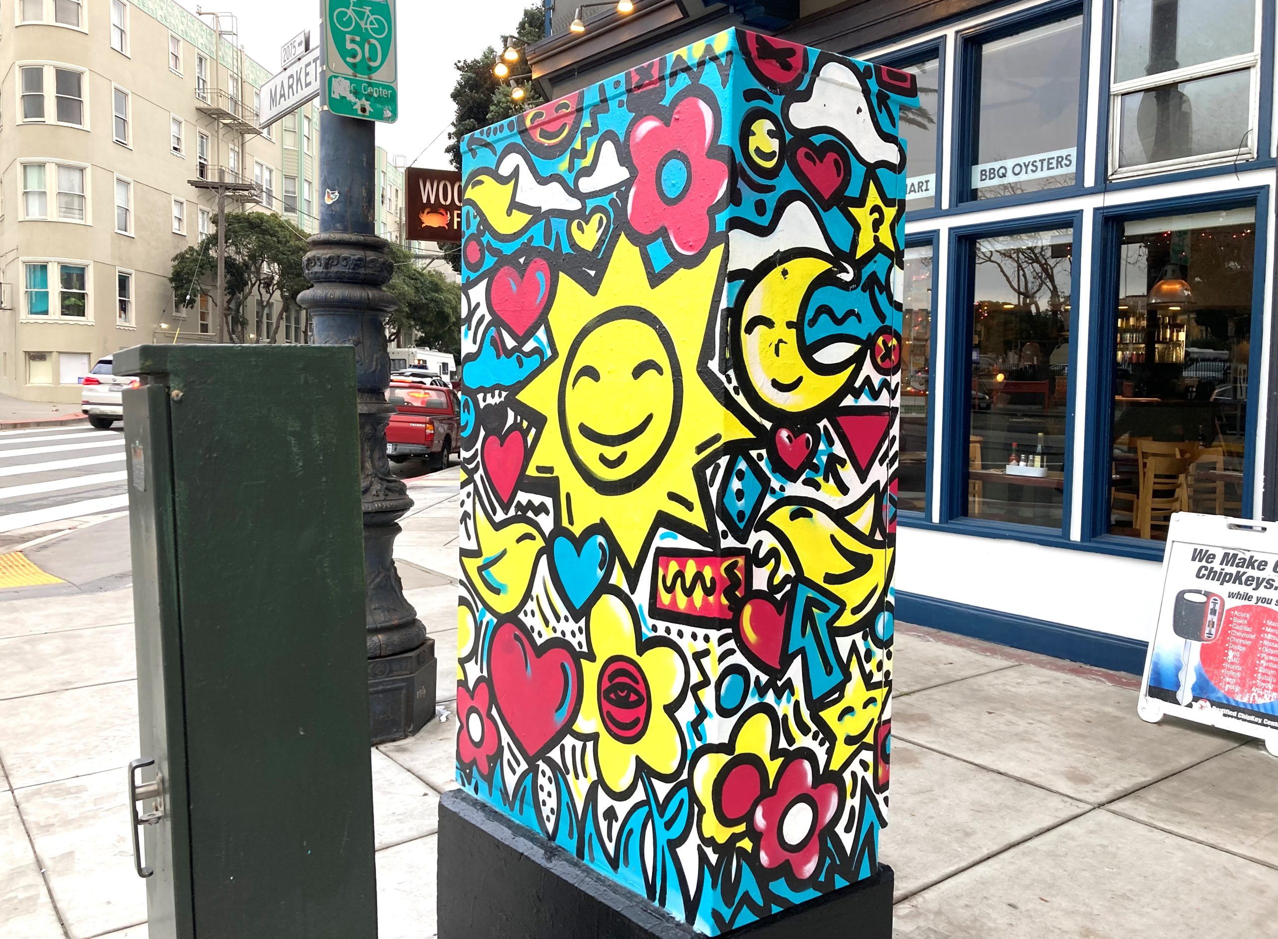 Smiley faces painted in bright colors on an electric box by the side of the street.
